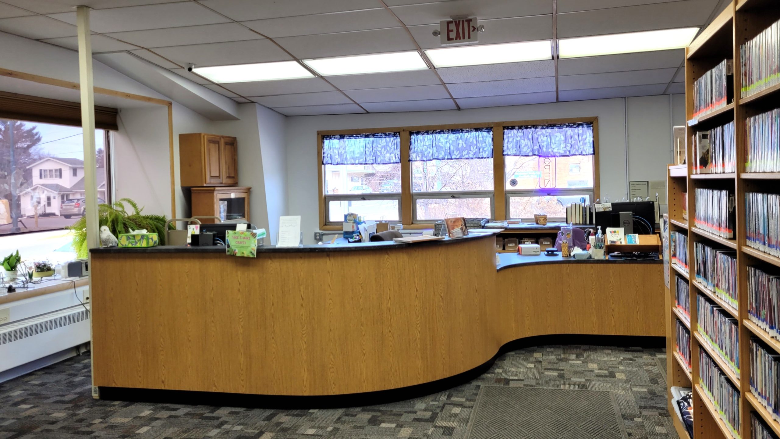Interior of a library with a wooden reception desk and shelves of DVDs.