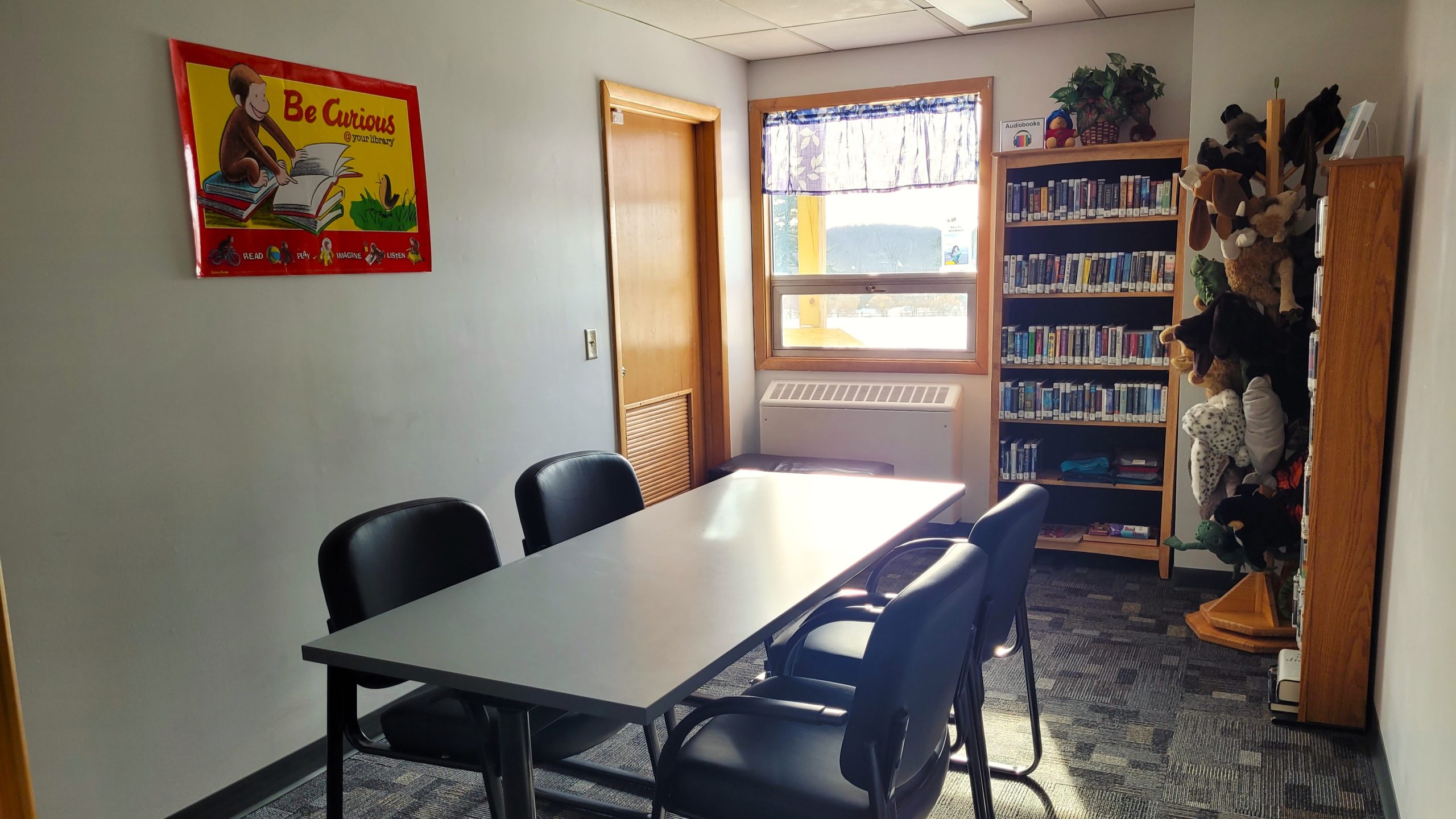 Library room with a table, chairs, and bookshelves filled with audiobooks.