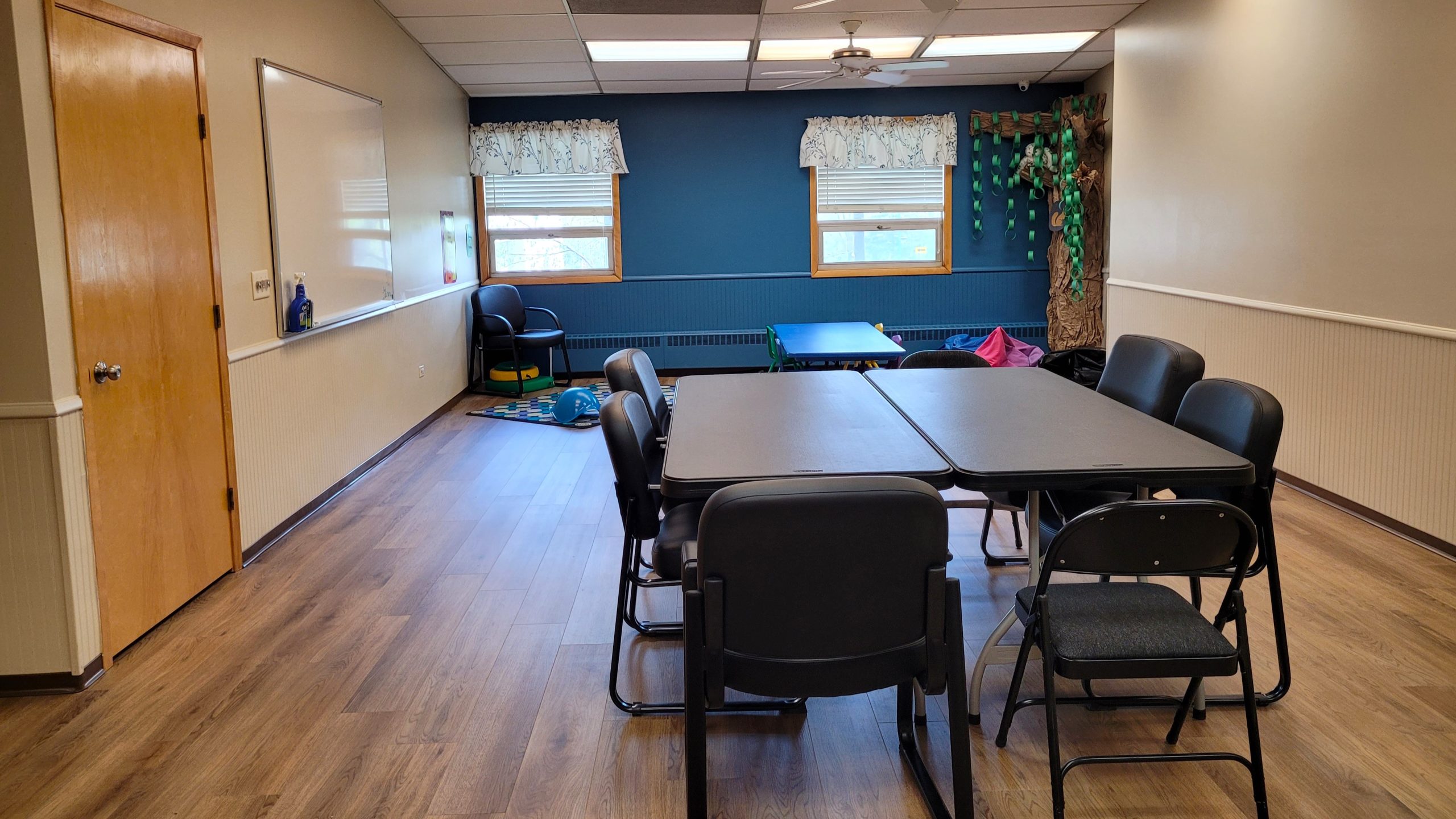 Multipurpose room with tables, chairs, and a decorative corner tree.